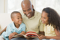 A smiling man reading a book with his children at home