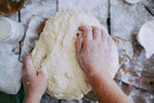 A close-up view of a baker kneading dough