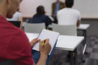 Male student taking notes in classroom