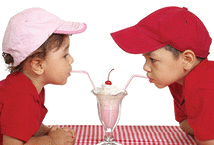 Cute two- and three- year-old boy and girl sharing a milk shake
