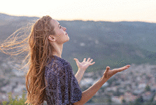 A young woman with her hands raised in worship and praise to god