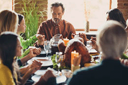 A family prays and hold hands at a Thanksgiving dinner.