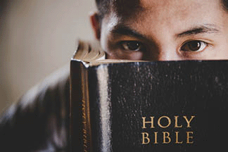 close-up of young student reading a holy Bible and looks at the camera!