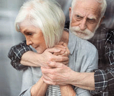 Upset senior man hugging wife, sick on dementia