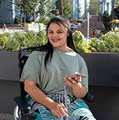 A young happy disabled woman in wheelchair using smartphone