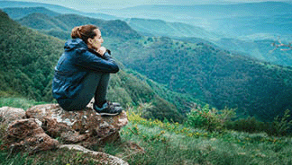 Sad depressed woman sitting on rock