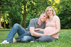 A pregnant couple in the park.