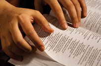 Hands of a person searching through the Bible.