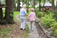 Elderly couple walking though a garden.