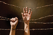 Hands behind barbed wire