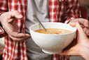 Homeless man being handed a bowl of soup.